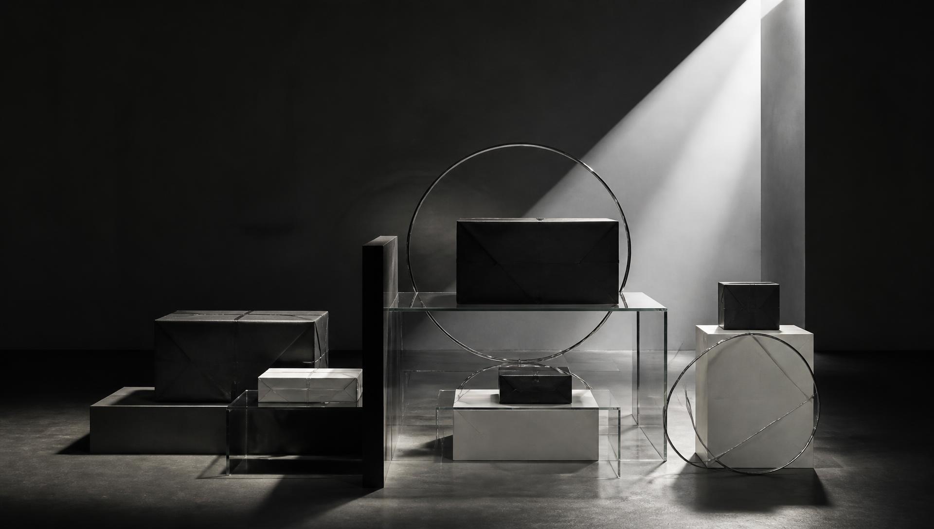 A sculptural system of ecommerce parcels, glass planes and chrome rings in a beam of light